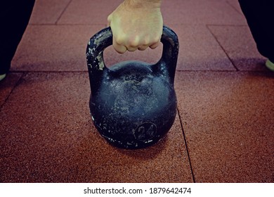 Hand Holding Kettlebell On The Floor. 