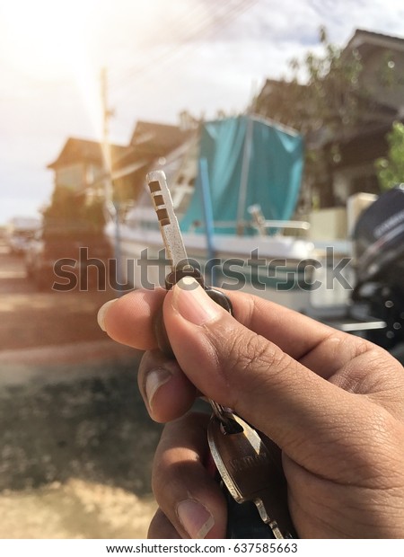 Hand\
holding the key with boat background and copy\
space.