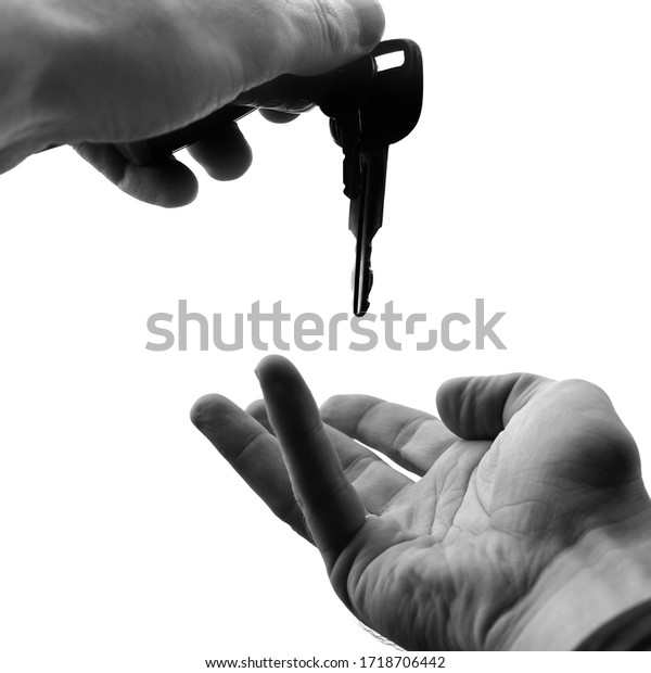 Hand holding a key and an empty\
palm close-up isolated on a white background. Car\
sharing.