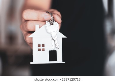 Hand holding the key and home shaped keychain. Mortgage, investment, real estate, property and new home concept. - Powered by Shutterstock