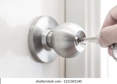 Hand holding the key to unlock the door knob. open the door