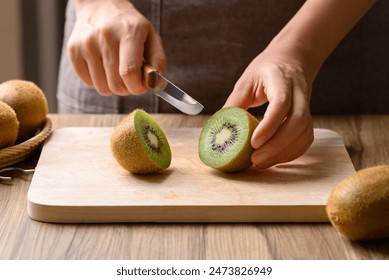 Hand holding kitchen knife and cutting kiwi fruit on wooden board, Homemade cooking - Powered by Shutterstock