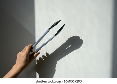 Hand Holding Kitchen Tongs On Background Isolated