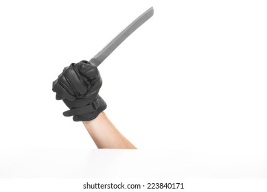 The Hand Is Holding The Knife With Black Leather Glowes. Isolated On A White Background.