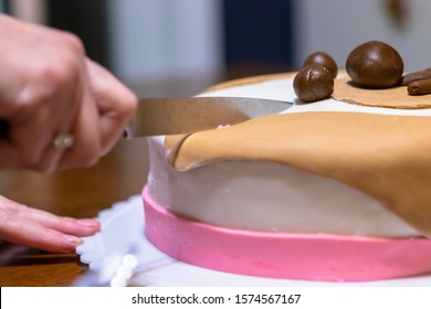 Hand Holding Knife Cutting Through Birthday Cake