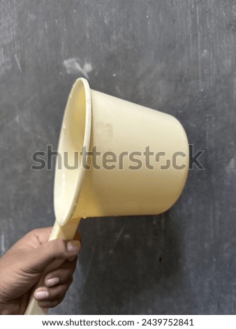 Hand holding a ladle on a gray background