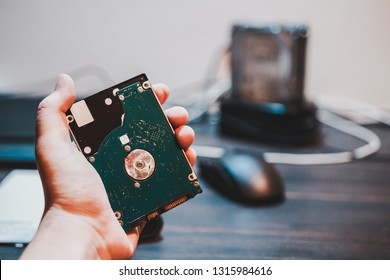 Hand Holding Laptop Hard Drive Use To Store Files And Data With Desktop Hard Drive In The Docking Station In The Background