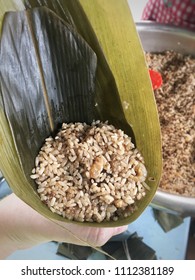 A Hand Holding Leaf Filled By Sticky Rice To Make Zongzi. The Traditional Chinese Rice Dumplings For Dragon Boat Festival