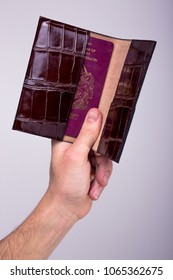 A Hand Holding A Leather Passport Holder