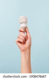 Hand holding a LED light bulb on blue background. Using economical and environmentally friendly light bulb concept. Idea. Energy saving lamp in woman's hand