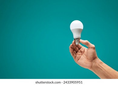 Hand holding a LED light bulb isolation on green background. Male hand demonstrating Eco power light bulb. Innovation inspiration concept. Copy space. - Powered by Shutterstock