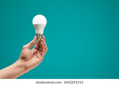 Hand holding a LED light bulb isolation on green background. Male hand demonstrating Eco power light bulb. Innovation inspiration concept. Copy space. - Powered by Shutterstock