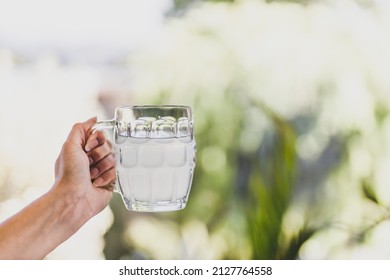 hand holding lemon water or lemonade in beer stein glass in front of sunny backyard bokeh, concept of summer relaxation and drinks - Shutterstock ID 2127764558