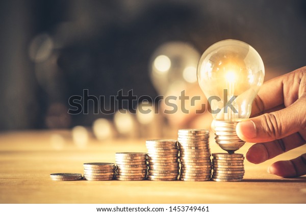 Hand\
holding a light bulb with coins stack. Creative ideas for saving\
money concept. Money management for the future\
