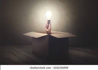 hand holding light bulb coming out from a paper box
