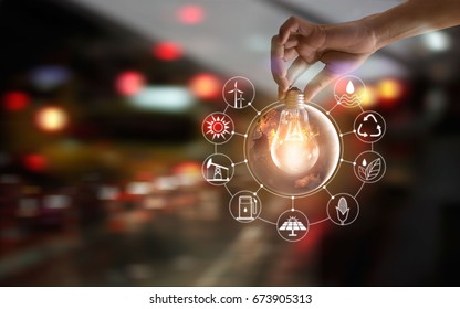 Hand holding light bulb in front of global show the world's consumption with icons energy sources for renewable, sustainable development. Ecology concept. Elements of this image furnished by NASA.
