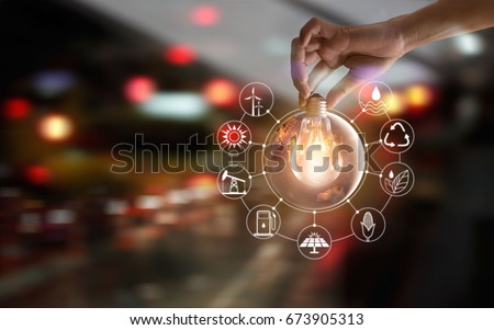 Hand holding light bulb in front of global show the world's consumption with icons energy sources for renewable, sustainable development. Ecology concept. Elements of this image furnished by NASA.
