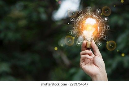 Hand holding light bulb with icons energy, Sustainable development and Ecology concept. - Shutterstock ID 2233754547