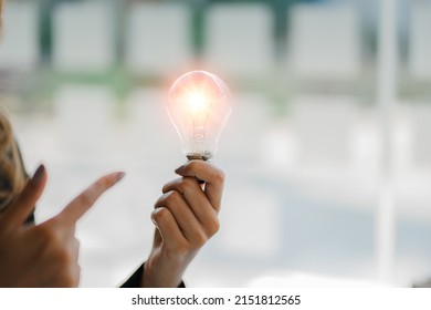 Hand holding a light bulb. Innovative and inspirational concepts looking for new ideas for designing, working better with innovation and saving energy.