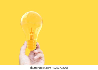 Hand Holding Light Bulb Yellow Pastel Color On Yellow Background With Clipping Path, Idea And Minimal Concept.