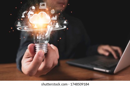 Hand Holding Lightbulb With Cloud Computing And Technology Icons Such As Laptop Computer Graph.Cloud Technology Management Big Data Include Business Strategy , Customer Service.