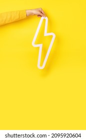 Hand Holding Lightning Bolt Icon Over Yellow Background