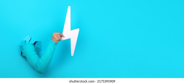 Hand Holding Lightning Bolt Over Blue Background, Panoramic Layout