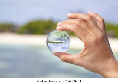 Hand Holding A Little Glass Ball With Beautiful Beach View