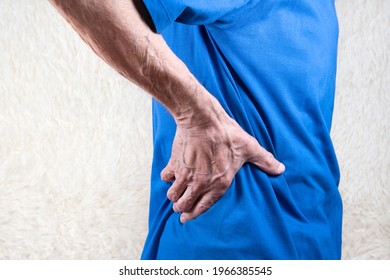 hand holding lower back, elderly man suffering from pain in side. White background