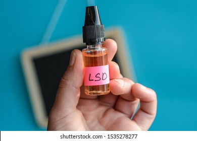 Hand holding LSD liquid bottle. Conceptual image of diluted LSD used for micro dosing 