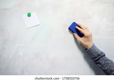 Hand Holding Magnetic Eraser Sponge On Dirty White Board And Paper Attached With A Magnet.