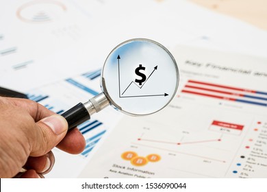Hand holding magnifier glass for searching US dollar sign and financial report.Value investor find the best stock on market.