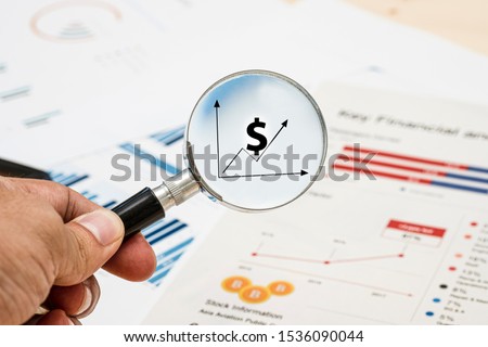 Hand holding magnifier glass for searching US dollar sign and financial report.Value investor find the best stock on market.