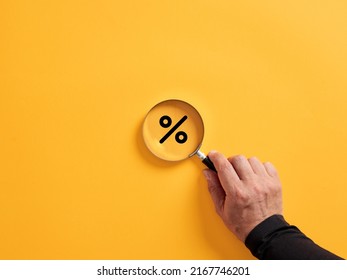 Hand holding a magnifier over the percent or percentage symbol. Searching for sale or discount concept. - Powered by Shutterstock