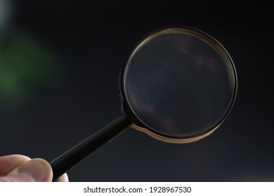 hand holding magnifying glass in dark room. concept of uncovering mystery, detective investigation, solve secret