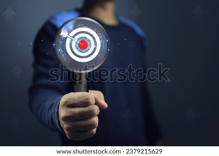 Hand holding magnifying glass with dart board represent to goal researching information and market study before starting a business to achieve target success to goal with least of time and resources