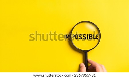 Hand holding magnifying glass with possible and impossible words on the yellow background. Optimistic and Business metaphor concept.