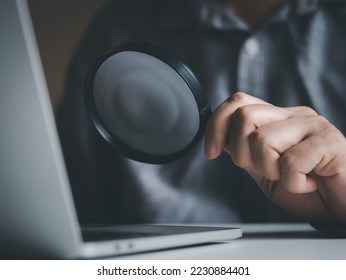 Hand holding magnifying glass for searching or finding information in laptops via online internet computer network. Internet online searching concept. - Shutterstock ID 2230884401