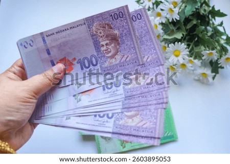Hand holding Malaysian Ringgit banknotes and money packet (sampul duit raya) for Ramadan and Eid Fitr Celebration.