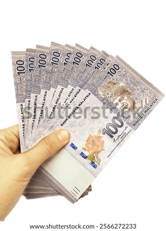 Hand holding Malaysian Ringgit (RM 100) banknote on isolated white background 