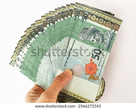 Hand holding a Malaysian Ringgit (RM 50) banknote on isolated white background 