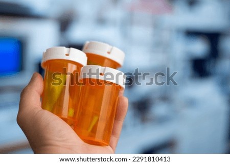 Hand holding many empty orange bottles of medicine in a hospital
