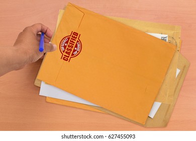 Hand Holding Marker And Classified Top Secret Manila Envelope Mail Desk