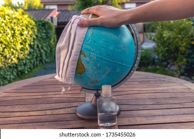 Hand Holding A Mask On A Earth Globe Represents The Global Pandemic