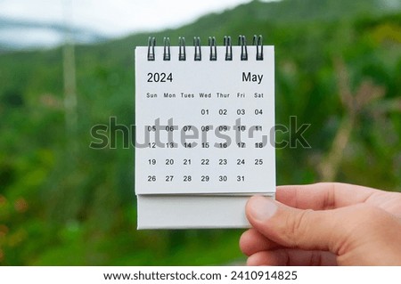 Hand holding May 2024 white calendar with nature background. Holiday and calendar concept.