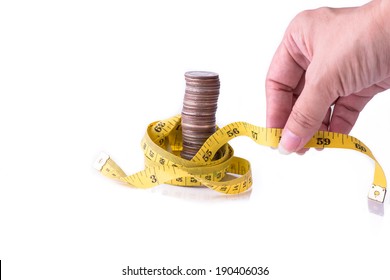 Hand holding measuring tape with stack of coins isolated on white