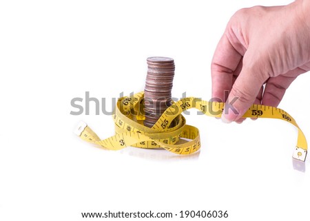 Hand holding measuring tape with stack of coins isolated on white