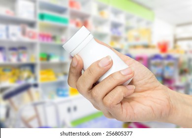 Hand Holding Medicine Bottle In Pharmacy