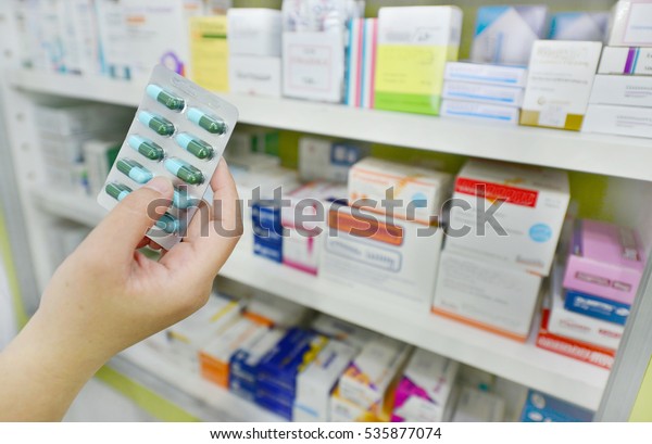 Hand holding medicine capsule pack at the pharmacy drugstore.