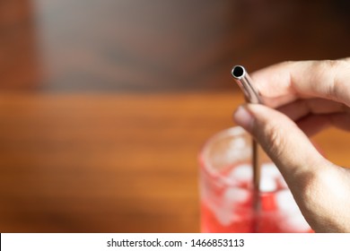 Hand Holding Metal Straw In A Glass Of Red Sweet Drink